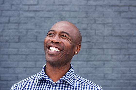 A black man with dental implants is smiling